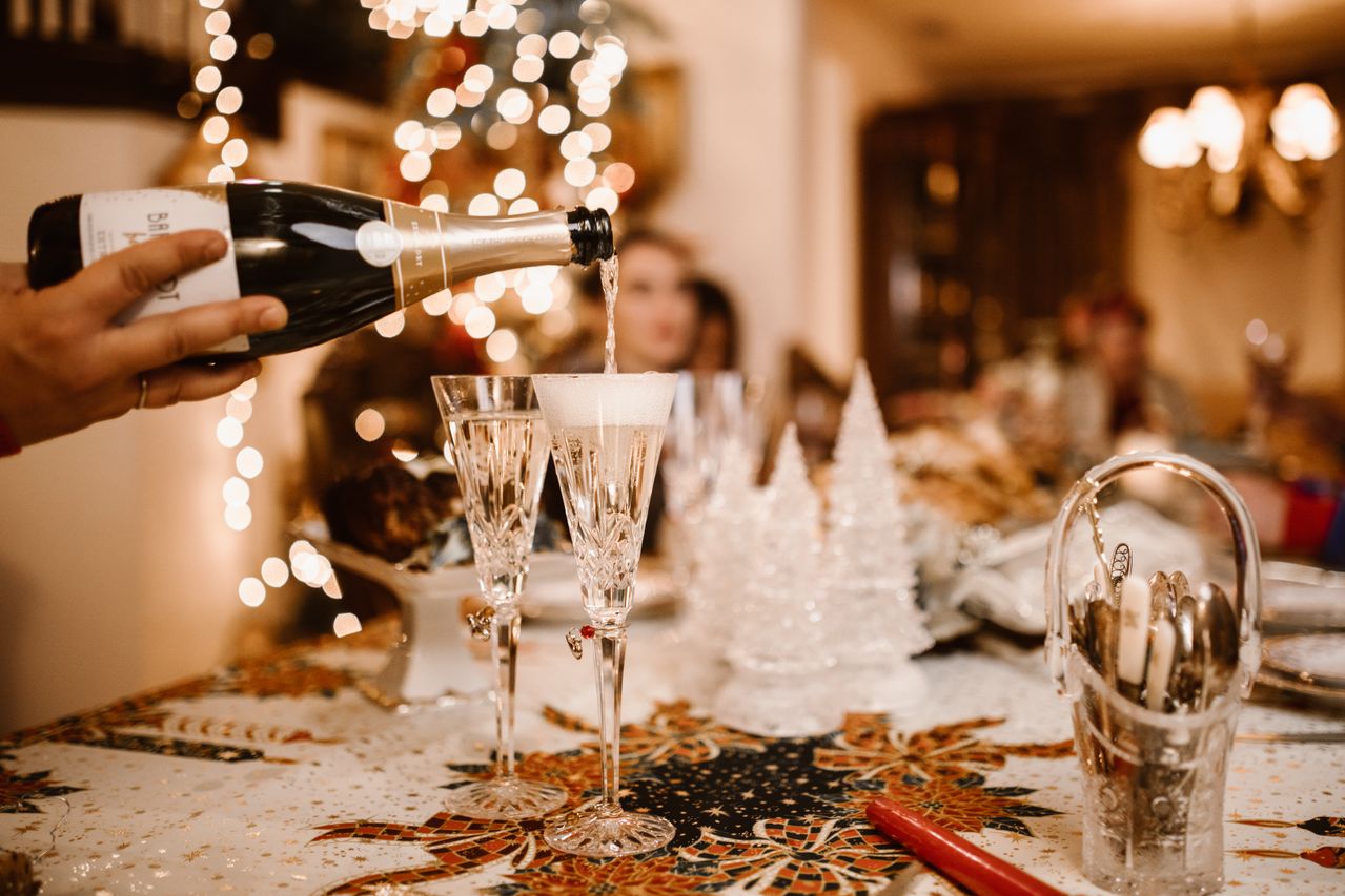 Flourish Dinner | Lucera Studio | Lucera Studio Champagne being poured into a flute at a dinner table with Christmas lights in the background.
